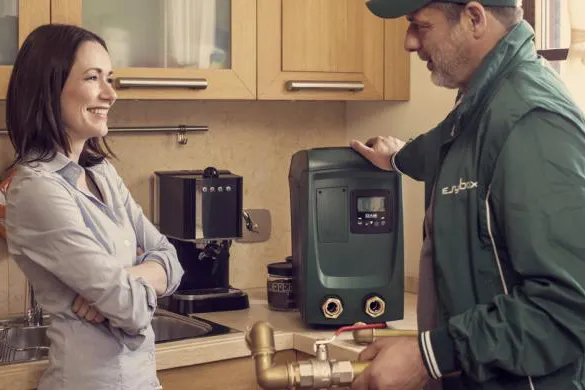 dab-pumps-installation-service-L251209 Professional technician demonstrating DAB E.sybox Mini installation to homeowner in residential kitchen setting